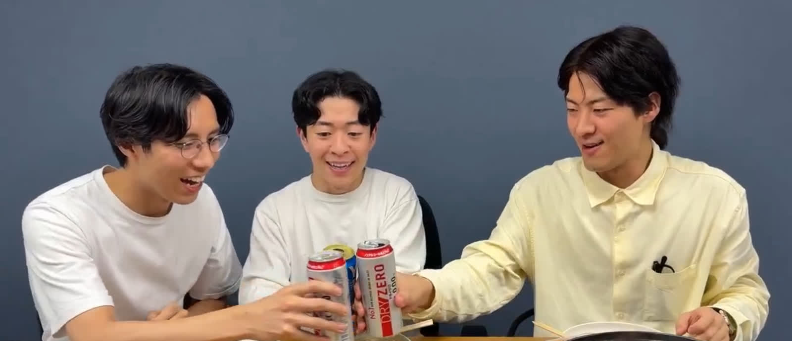 毛ガニ鍋を囲み、3人で缶を合わせて乾杯する様子